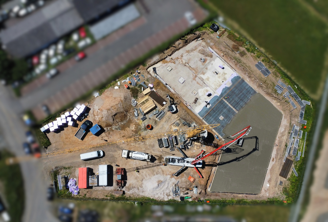 Drone view of the construction site showing the poured foundation and construction vehicles